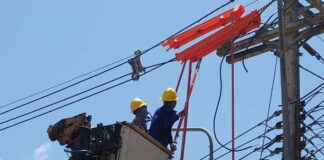 Electricite Du Laos workers repair an electricity line