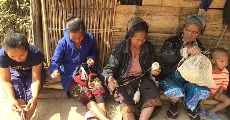 Four Khmu artisans demonstrate the stage of creating a Nature Bag from a plant stem while a young boy makes it a family affair.