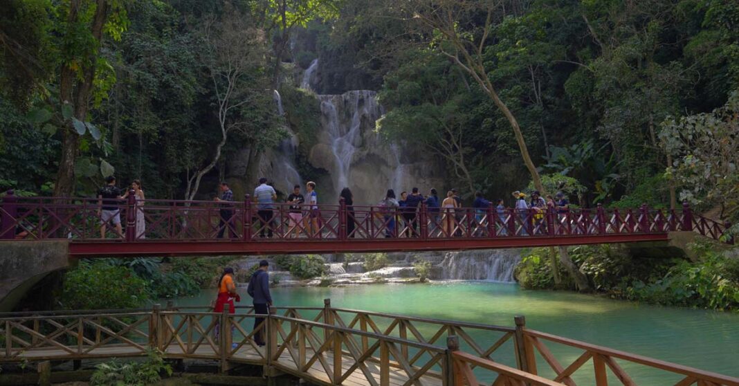 Tourists visit a waterfall in Luang Prabang