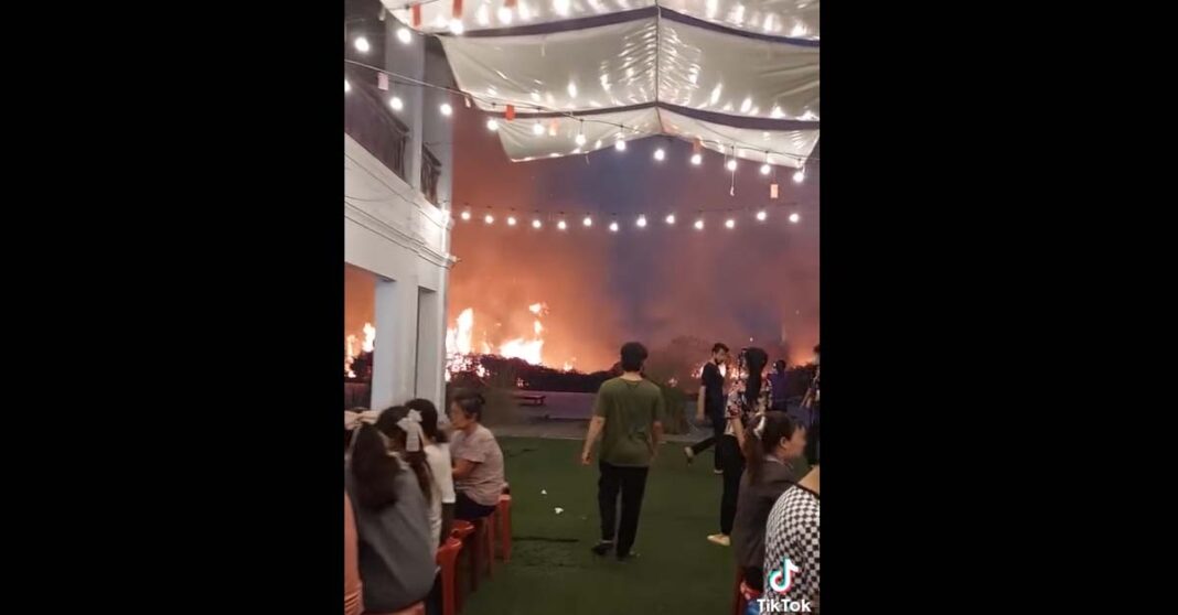 A brushfire by a restaurant along the Mekong River