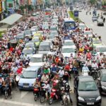 A swarm of motorbikes stopped at a traffic light in Hanoi.