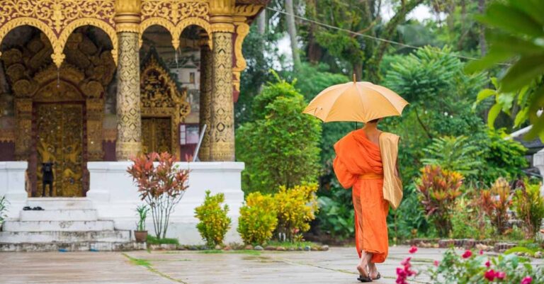 Monk in Laos walks through a temple in the rain