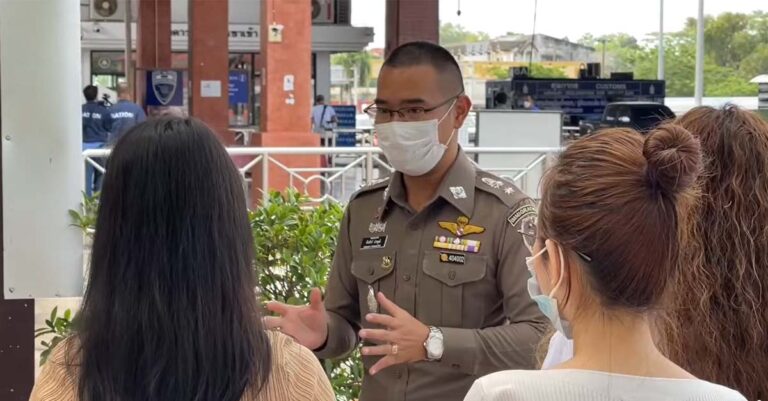 Thai immigration official speaks with Lao citizens entering Thailand