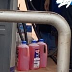 An individual fills milk bottles with fuel.