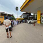 Residents in Vientiane line up to fill plastic bottles with petrol.