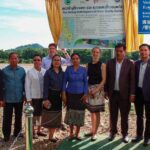 Delegates from the Lao Government, MRC Secretariat, and embassies pose for a group photo in front of the signboard of the new water quality monitoring station.
