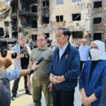 In this photo released by the Press and Media Bureau of the Indonesian Presidential Palace, Indonesian President Joko Widodo, center, and his wife Iriana, right, talk to the media near an apartment building damaged by shelling, during his visit in the town of Irpin on the outskirts of Kyiv, Ukraine on Wednesday, June 29, 2022. (Laily Rachev, Indonesian Presidential Palace via AP)