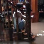 A man surveys the floodwaters in his home from the safety of the staircase