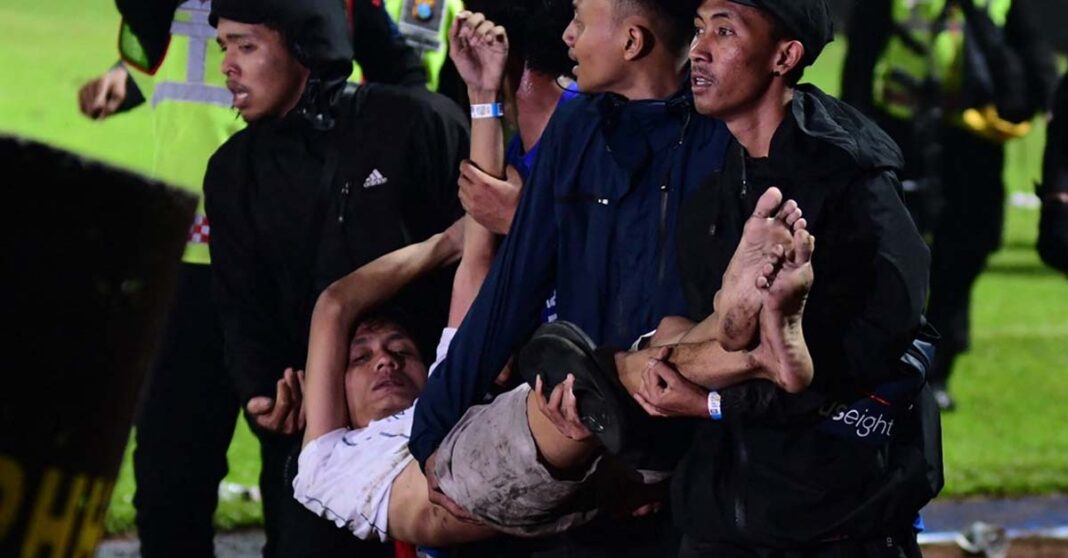 Police carry an injured man from the field during a football riot in East Java.