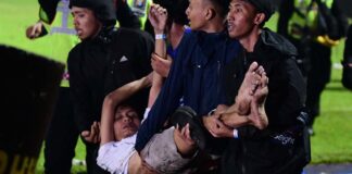 Police carry an injured man from the field during a football riot in East Java.