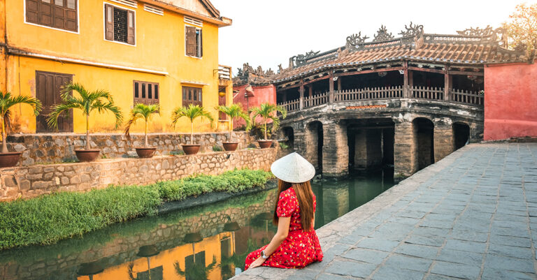 A woman sitting next to Thu Bồn river in Hoi An, Vietnam