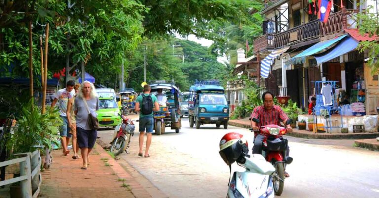 A tourist walks along the sidewalk in Laos.