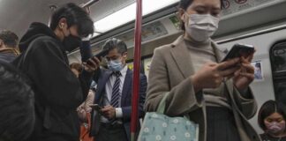 Commuters wearing face masks browse their smartphones as they ride on a subway train in Hong Kong on Feb. 7, 2023. Hong Kong will lift its mask mandate Wednesday, March 1, 2023, ending the city’s last major restriction imposed during the COVID-19 pandemic. (AP Photo/Andy Wong, File)