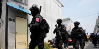 A group of armed commando police leave from the home of a senior police officer in Bangkok, Thailand, Wednesday, March 15, 2023. Thai police have arrested a fellow officer who fired multiple gunshots from his home in Bangkok which forced an over 24 hours-long standoff after his colleagues tried to take him to be treated for mental illness. (AP Photo/Sakchai Lalit)