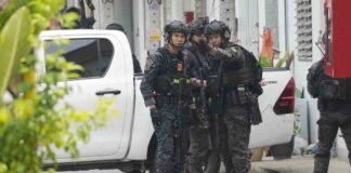 Members of the armed commando police are seen outside a home of a senior police officer in Bangkok, Thailand, Wednesday, March 15, 2023. Thai police on Wednesday detained the senior police officer who fired multiple gunshots from his home in Bangkok, ending a standoff of over 24 hours after his colleagues tried to take him to be treated for mental illness. (AP Photo/Sakchai Lalit)