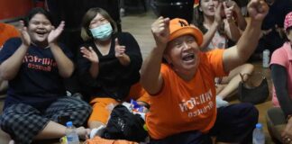 Supporters of Move Forward party cheer as they watch the counting of votes on television at Move Forward Party headquarters in Bangkok, Thailand