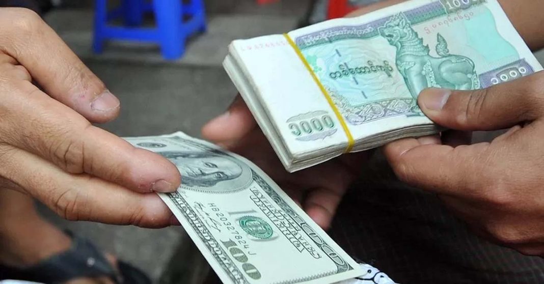 Stacks of Myanmar kyat sit on a counter at a bank