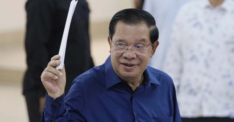Cambodian Prime Minister Hun Sen of the Cambodian People's Party raises a ballot before voting at a polling station (AP Photo - Heng Sinith)