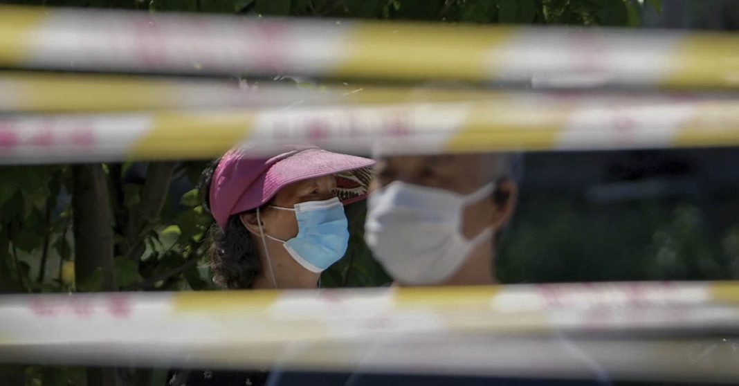 FILE - Residents wearing face masks line up behind barricaded tapes for COVID mass testing near a residential area on May 15, 2022, in Beijing. The World Health Organization says it’s made an official request to China for information about a potentially worrying spike in respiratory illnesses and clusters of pneumonia in children. (AP Photo/Andy Wong, File)