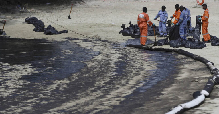 Workers clean oil spill along Sentosa's Tanjong Beach area in Singapore, Sunday, June 16, 2024. An oil spill caused by a dredger boat hitting a stationary cargo tanker has blackened part of Singapore's southern coastline, including the popular resort island of Sentosa, and sparked concerns it may threaten marine wildlife. (AP Photo/Suhaimi Abdullah)