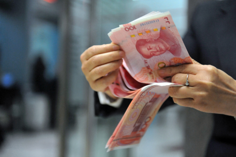 A bank employee counts 100-yuan banknotes at a bank in Hangzhou, east China's Zhejiang province on December 1, 2015 CHINA OUT AFP PHOTO (Photo by AFP)