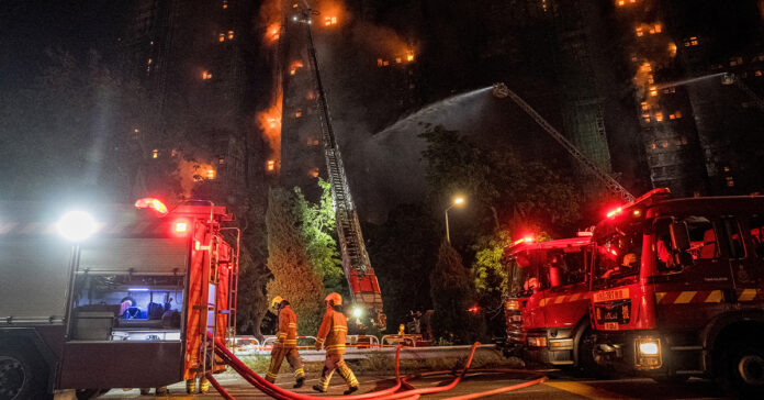 Firefighters spray water on flames as a major fire engulfs several apartment blocks at the Wang Fuk Court residential estate in Hong Kong's Tai Po district on November 26, 2025. A huge fire ripped through several high-rise blocks in a Hong Kong residential estate on November 26, killing at least 13 people, with media reporting that some residents were trapped inside.